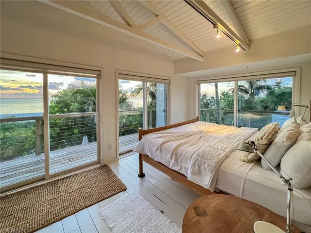 Bedroom with wooden ceiling, rail lighting, light wood-type flooring, beamed ceiling, and access to outside