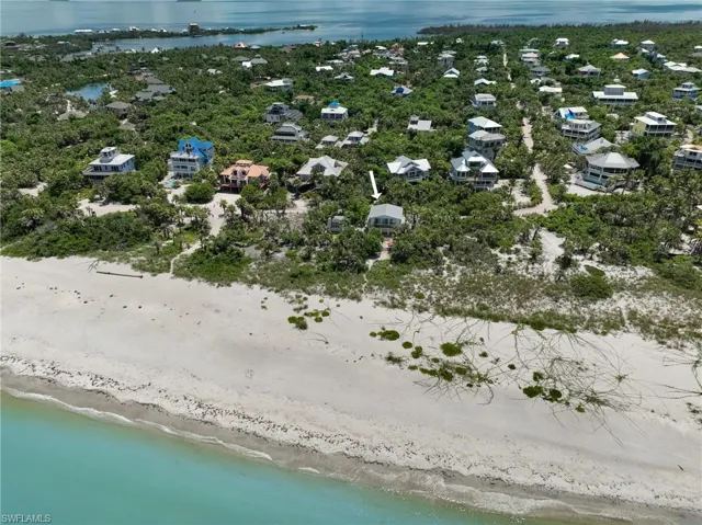 Birds eye view of property featuring a water view and a beach view