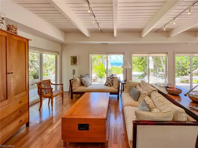 Living room with beamed ceiling, track lighting, and light hardwood / wood-style floors