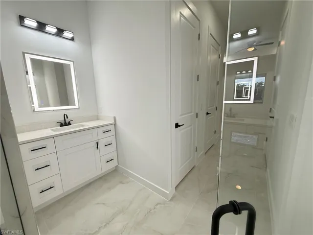 Bathroom with marble look tiles, vanity, and ceiling fan