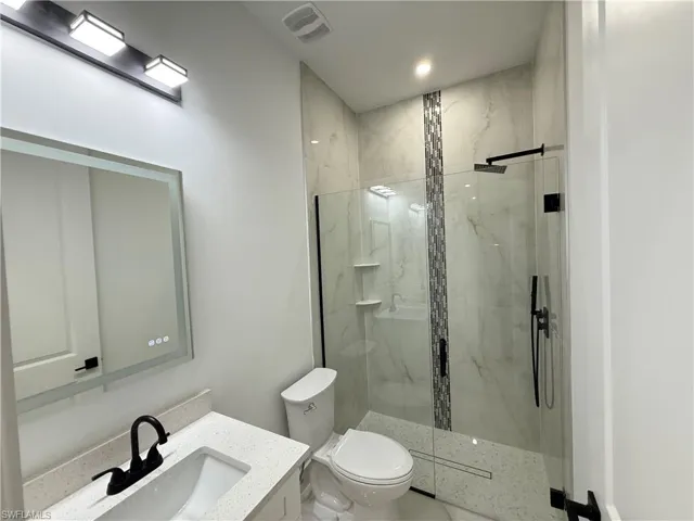 Bathroom with vanity and a marble finish shower