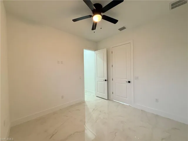 Empty room with light marble finish floors and a ceiling fan