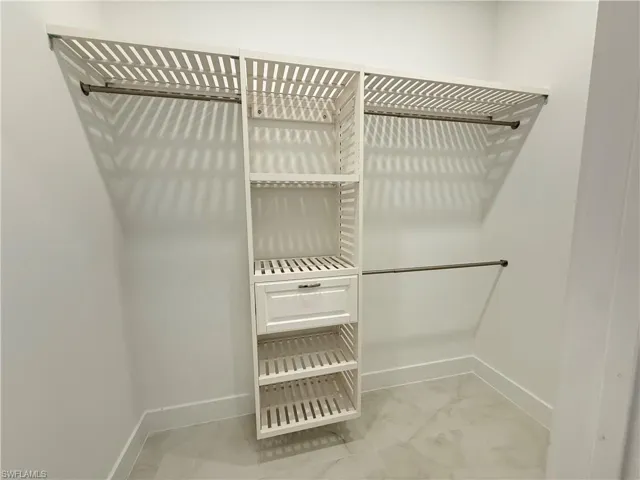 Spacious closet featuring light marble finish floors