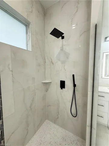 Bathroom featuring a marble finish shower and vanity