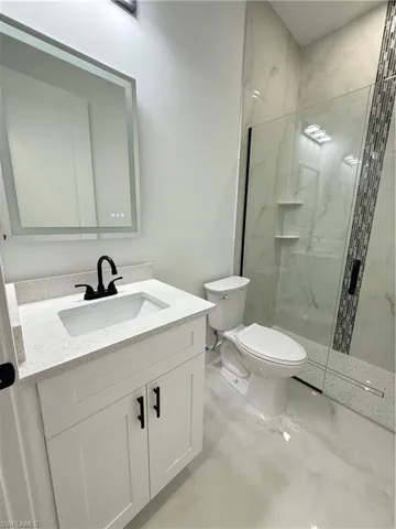 Bathroom featuring marble finish flooring, a marble finish shower, and vanity