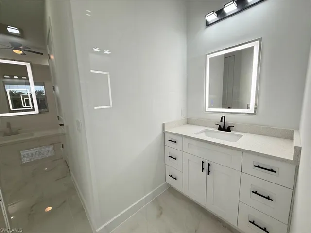 Bathroom with marble look tile flooring, vanity, and ceiling fan