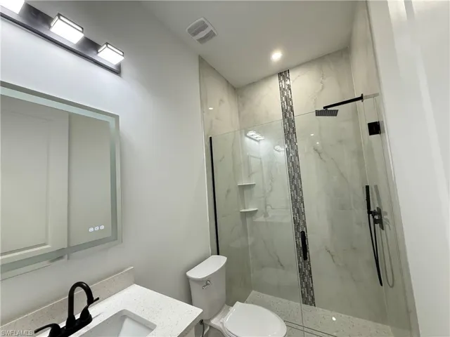 Bathroom with vanity and a marble finish shower