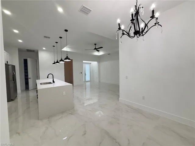 Kitchen with recessed lighting, ceiling fan, light marble finish flooring, stainless steel fridge, and open floor plan