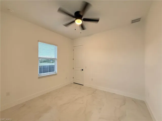 Empty room with a ceiling fan and light marble finish flooring