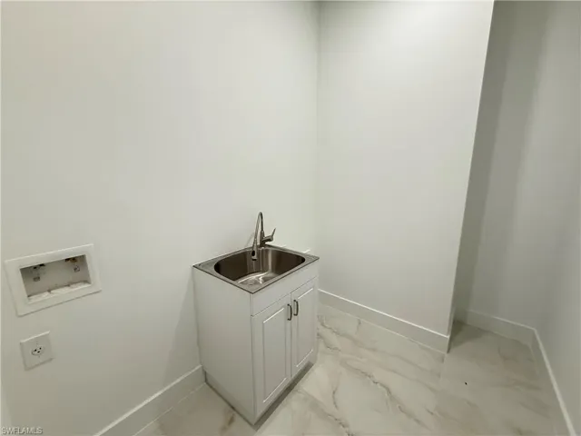 Washroom with hookup for a washing machine and light marble finish flooring