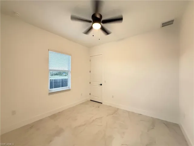 Spare room with light marble finish floors and ceiling fan