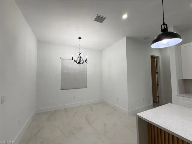 Unfurnished dining area with light marble finish floors and a chandelier