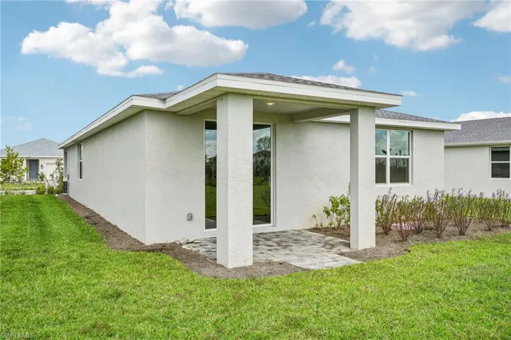 Rear view of property featuring a lawn and a patio