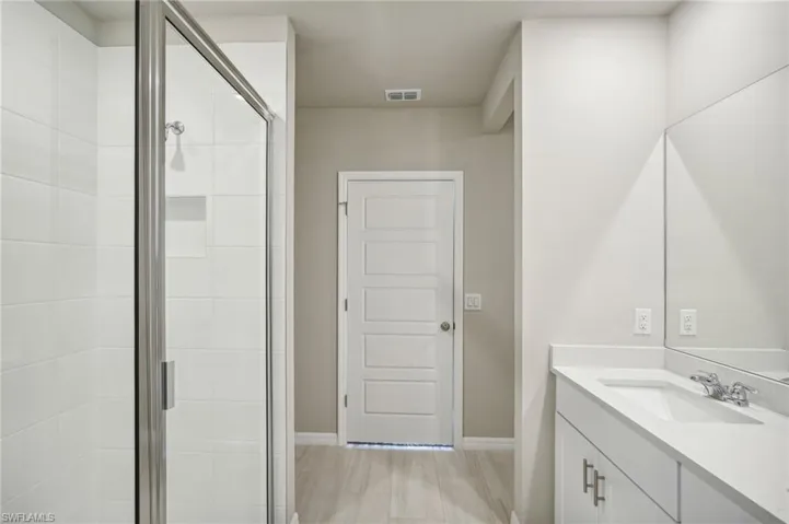 Bathroom with wood-type flooring, vanity, and an enclosed shower
