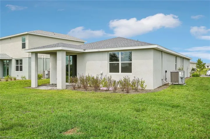 Rear view of property featuring a lawn and central AC