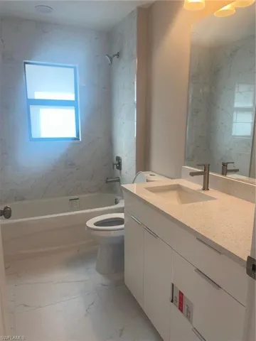 Full bathroom with vanity, toilet, and tiled shower / bath combo
