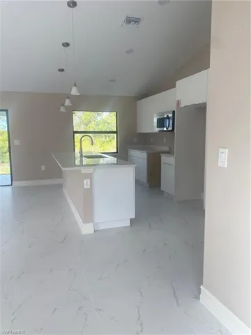 Kitchen featuring plenty of natural light, sink, hanging light fixtures, and white cabinets