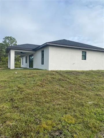Back of property with a yard and ceiling fan