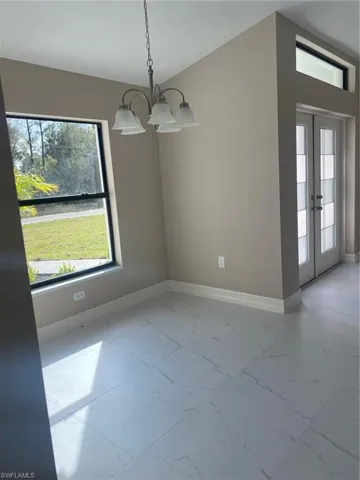 Unfurnished dining area with french doors and a chandelier