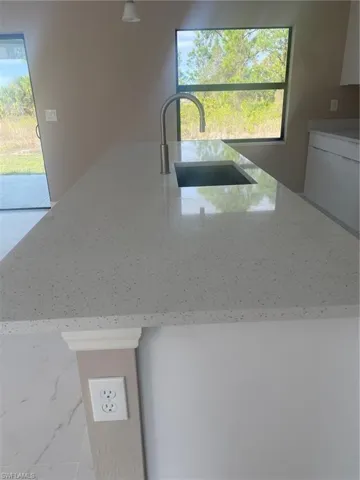 Kitchen with sink, light stone countertops, and a healthy amount of sunlight