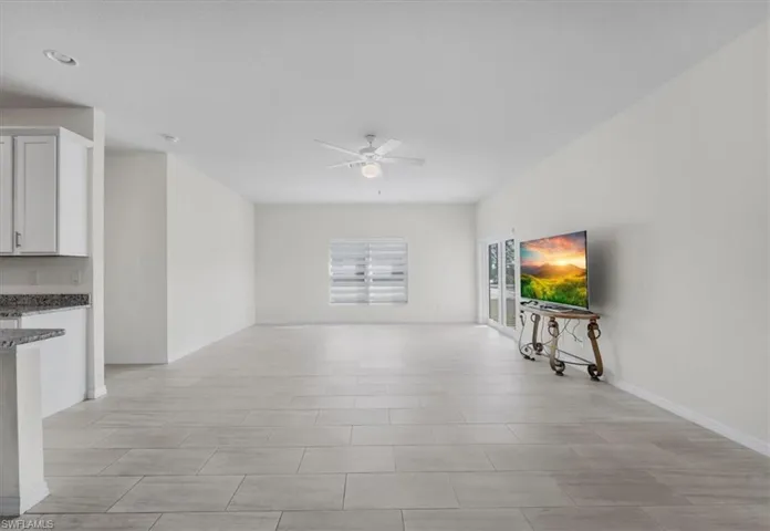 Unfurnished living room featuring ceiling fan and baseboards