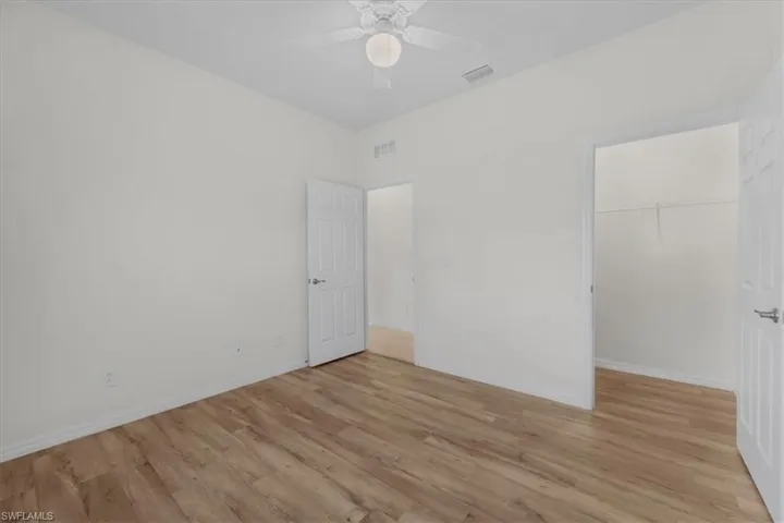 Unfurnished bedroom featuring a spacious closet, light wood-type flooring, and a ceiling fan