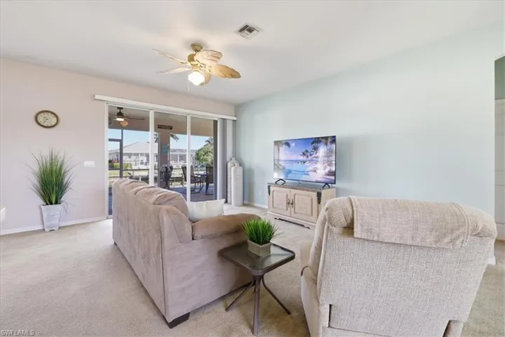 Living room with light colored carpet and a ceiling fan