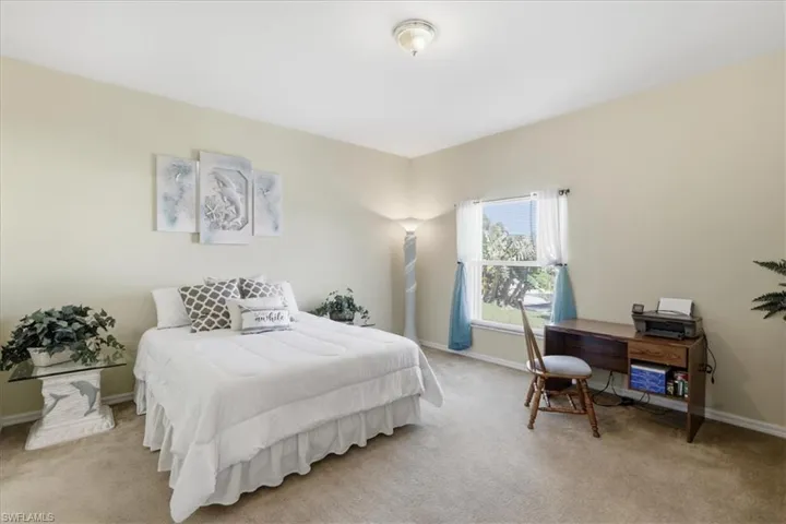 Bedroom featuring light carpet and an office area