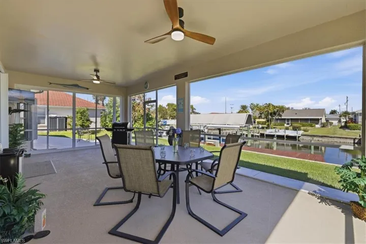 View of patio featuring a ceiling fan, a sunroom, outdoor dining area, and a dock