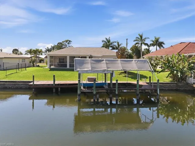 Dock featuring boat lift, a water view, a sunroom, and a lawn