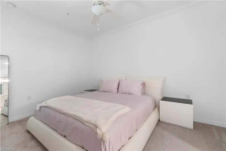 Carpeted bedroom featuring crown molding and ceiling fan