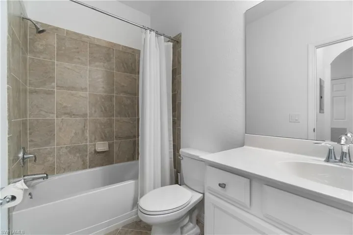 Full bathroom featuring tile patterned flooring, toilet, vanity, and shower / tub combo with curtain