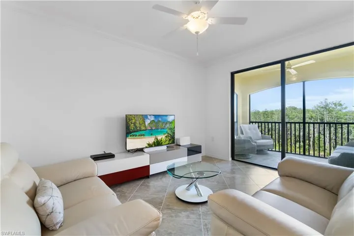 Living room with light tile patterned floors, ceiling fan, and crown molding