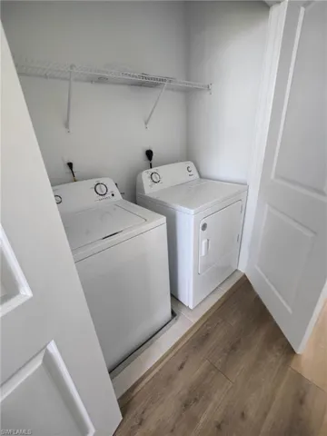 Washroom featuring hardwood / wood-style floors and washing machine and clothes dryer