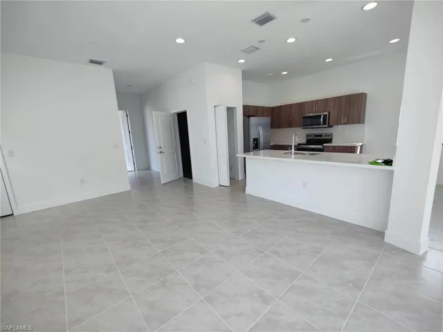 Kitchen with light tile patterned flooring, sink, and appliances with stainless steel finishes