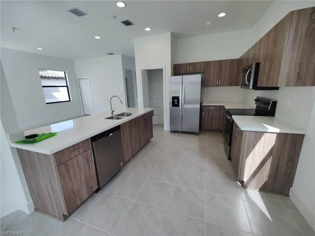 Kitchen with sink, light tile patterned floors, and stainless steel appliances