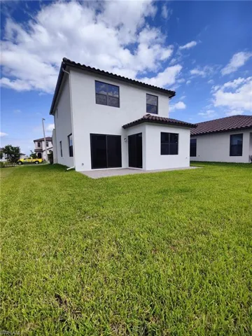 Rear view of property featuring a lawn and a patio