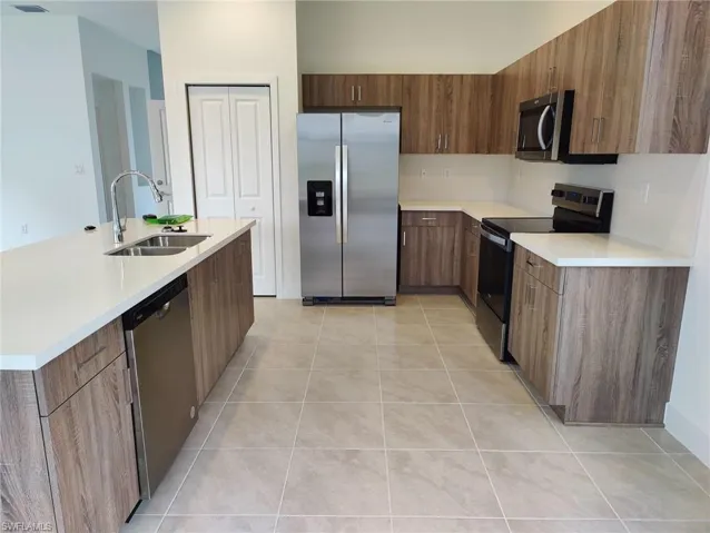 Kitchen featuring sink, light tile patterned floors, and stainless steel appliances