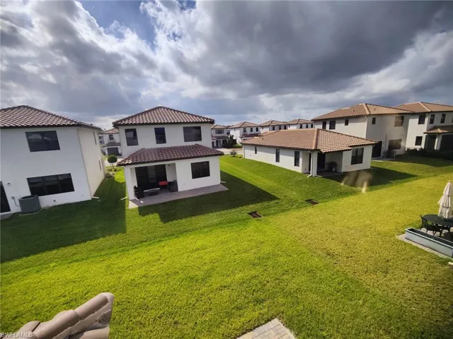 Back of property featuring a lawn, a patio area, and central AC
