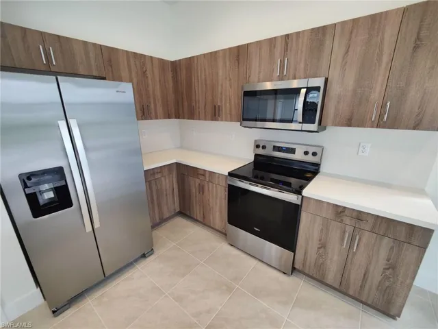 Kitchen featuring light tile patterned floors and appliances with stainless steel finishes