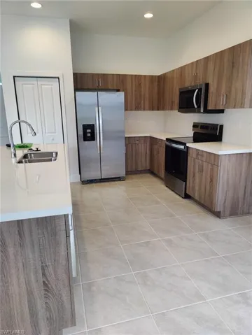 Kitchen with sink, light tile patterned floors, and stainless steel appliances