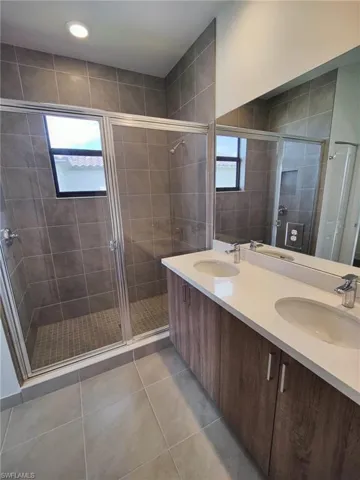 Bathroom featuring tile patterned flooring, vanity, a healthy amount of sunlight, and walk in shower