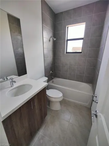 Full bathroom featuring tile patterned floors, toilet, vanity, and tiled shower / bath