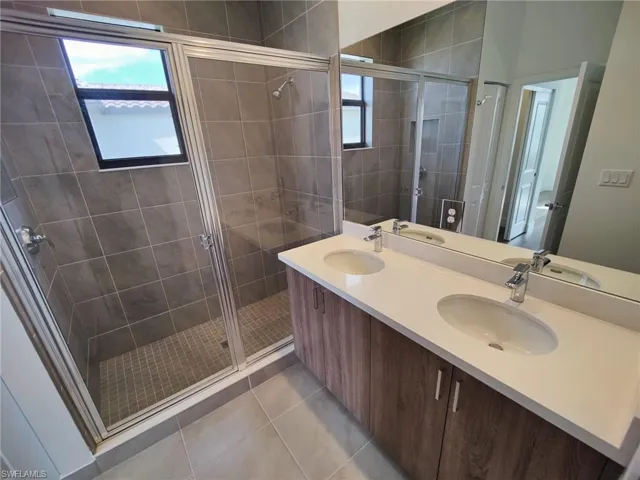 Bathroom with tile patterned floors, vanity, and a shower with door