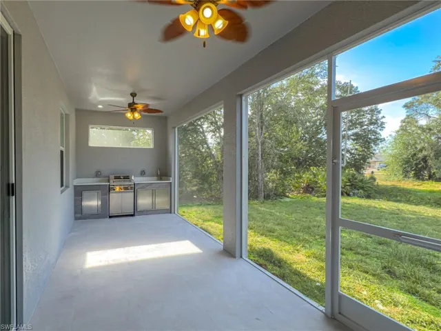 Unfurnished sunroom featuring a ceiling fan and an outdoor kitchen