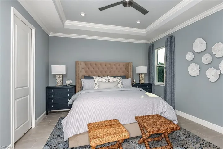 Bedroom with a raised ceiling, ornamental molding, ceiling fan, and recessed lighting