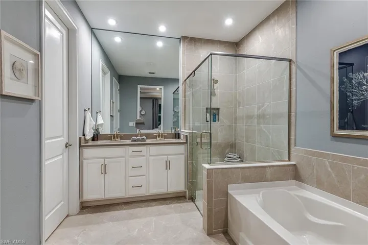Full bathroom featuring a bath, a stall shower, double vanity, and recessed lighting