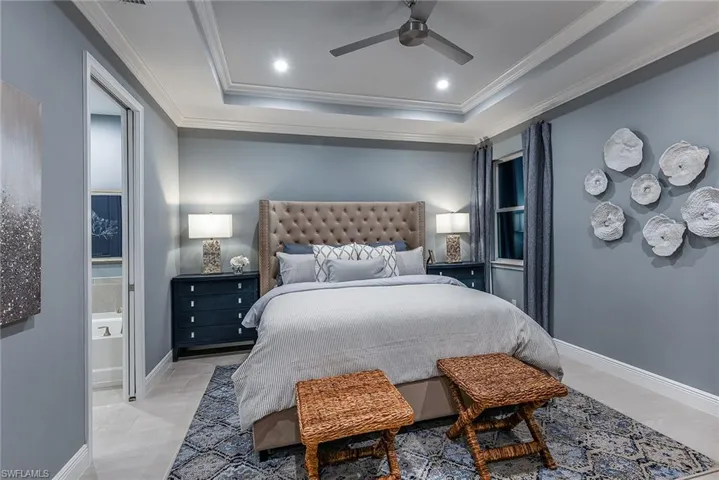 Bedroom with ornamental molding, a tray ceiling, ceiling fan, recessed lighting, and ensuite bathroom