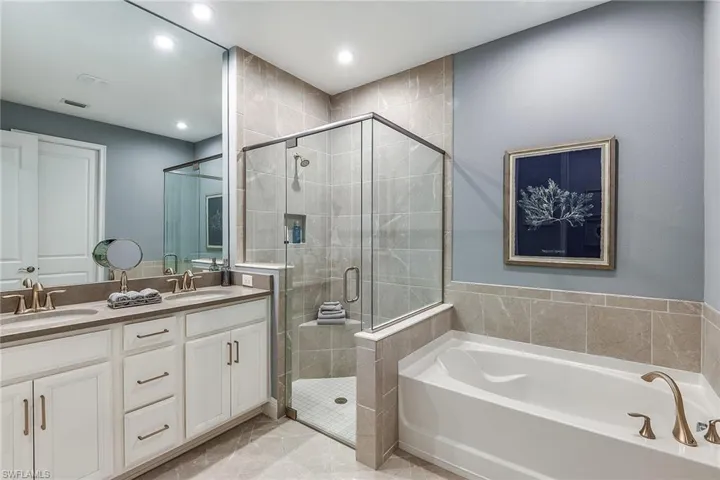 Full bath with a stall shower, a bath, double vanity, and recessed lighting