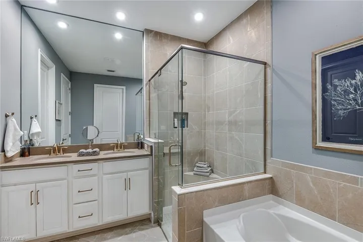 Bathroom featuring a stall shower, a bath, double vanity, and recessed lighting
